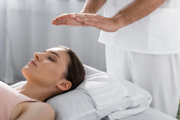 Cropped view of healer standing near patient on massage table and cleaning aura — Stock Photo