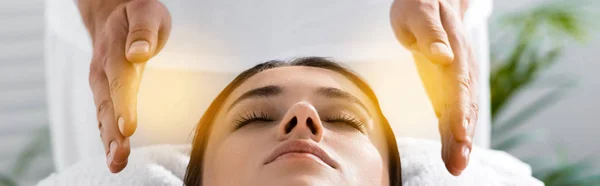 Panoramic shot of healer standing near patient on massage table and cleaning aura — Stock Photo