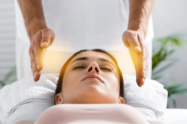 Vista cortada de curandeiro em pé perto do paciente na mesa de massagem e limpeza aura — Fotografia de Stock