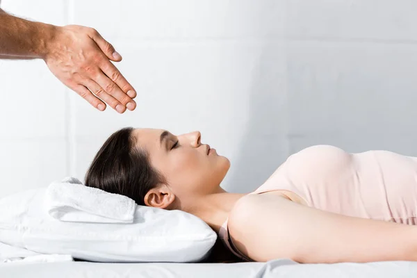 Vista recortada del sanador de pie cerca de la mujer y cogido de la mano por encima de su cabeza - foto de stock