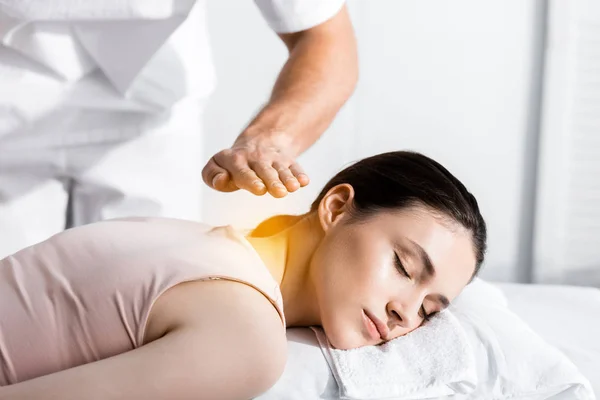 Ausgeschnittene Ansicht des Heilers, der neben einer Frau steht, die mit geschlossenen Augen liegt und die Hände über ihrem Körper hält — Stockfoto