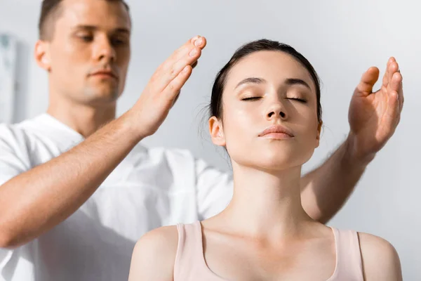 Woman sitting with closed eyes while healer cleaning her aura — Stock Photo