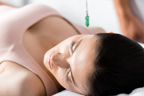 Mujer con los ojos cerrados y piedra verde sobre su cabeza - foto de stock