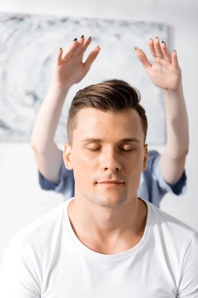 Front view of man sitting with closed eyes while healer cleaning his aura — Stock Photo