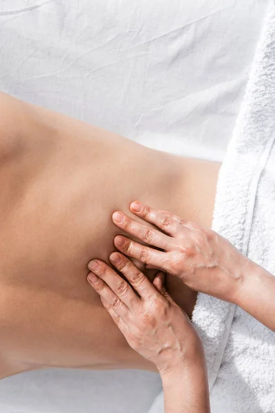 Cropped view of masseur and shirtless man lying on massage table — Stock Photo