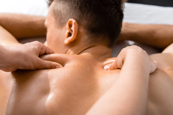 Vue recadrée du masseur et homme torse nu couché sur la table de massage — Photo de stock