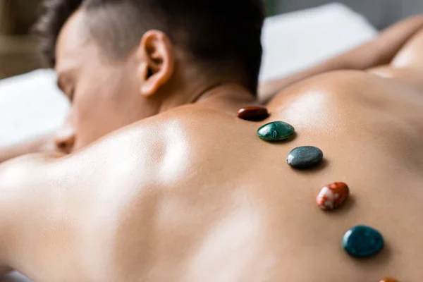 Selective focus of shirtless man with colorful stones on his back — Stock Photo