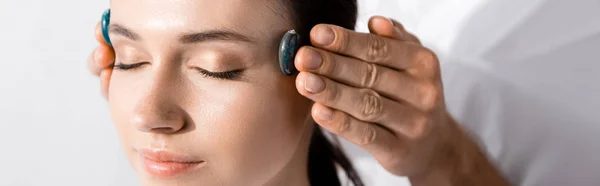 Panoramic shot of healer standing near woman with closed eyes and using stones — Stock Photo