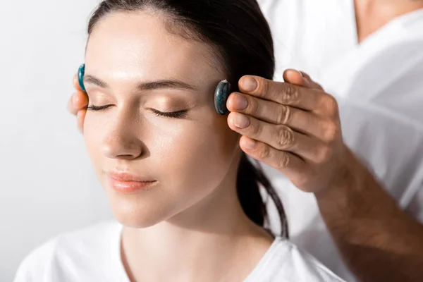 Vista recortada de curandero de pie cerca de la mujer con los ojos cerrados y utilizando piedras - foto de stock