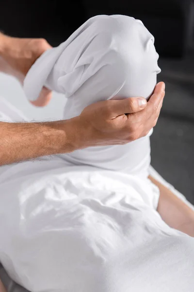 Обрезанный вид массажера, стоящего рядом с женщиной и трогающего ее ногу — стоковое фото