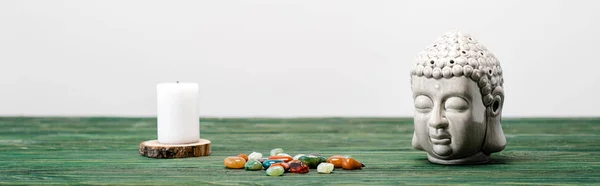 Plano panorámico de la estatuilla de buddha, vela y piedras semipreciosas de colores en la superficie de madera aislado en blanco - foto de stock