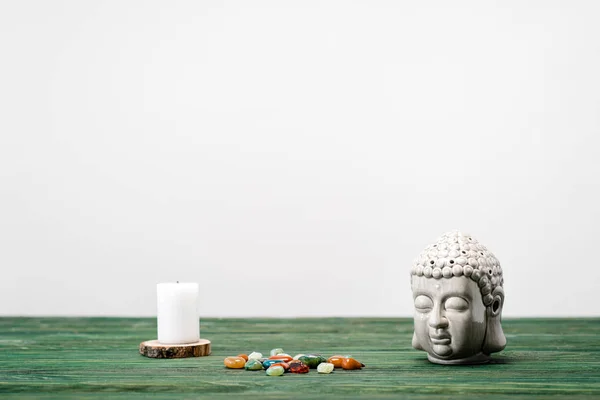 Estatuilla buddha, vela y piedras semipreciosas de colores en la superficie de madera aislada en blanco - foto de stock