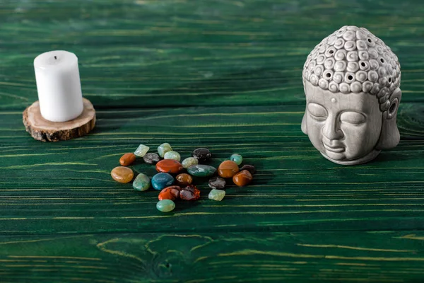 Buddha estatueta, vela e pedras semipreciosas coloridas na superfície de madeira — Fotografia de Stock