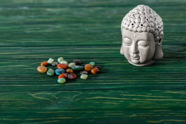 Buddha estatueta e pedras semipreciosas coloridas na superfície de madeira — Fotografia de Stock