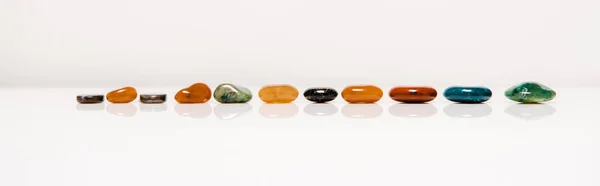 Panoramic shot of colorful semiprecious stones on white surface isolated on grey — Stock Photo