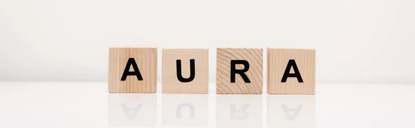 Panoramic shot of word aura lettering on wooden blocks on white — Stock Photo