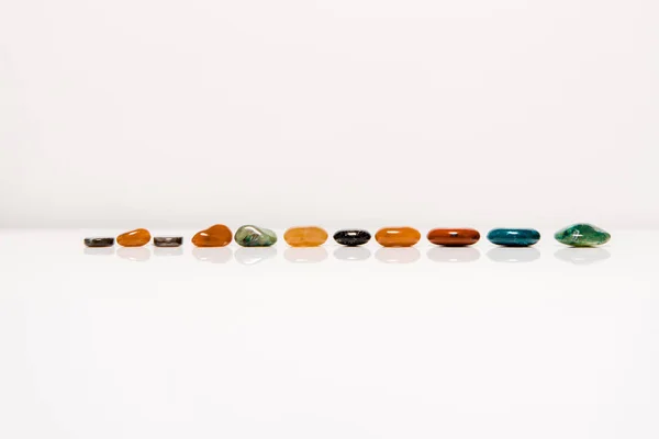 Colorful semiprecious stones on white surface isolated on grey — Stock Photo