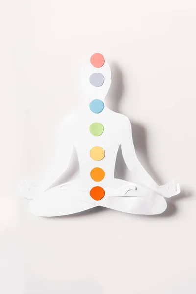 Visão superior de figura de papel na forma de pessoa com chakras em pose de lótus no branco — Fotografia de Stock