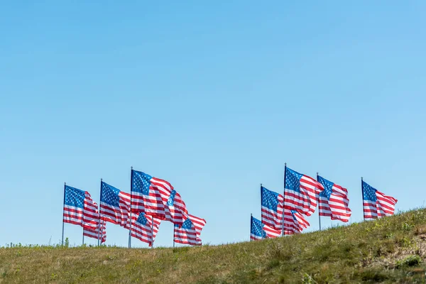 Amerikanische Flaggen mit Strohhalmen und Streifen auf grünem Gras vor blauem Himmel — Stockfoto