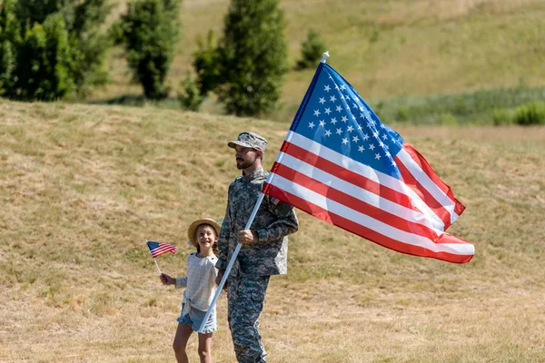 Homem militar e criança patriótica feliz segurando bandeiras americanas — Fotografia de Stock