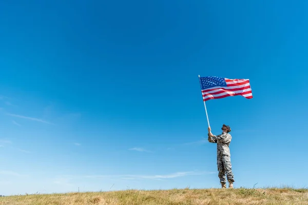 Bello militare uomo in uniforme guardando bandiera americana con stelle e strisce — Foto stock