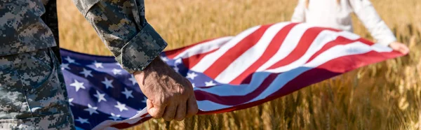 Panoramic shot of kid and military man holding american flag — Stock Photo