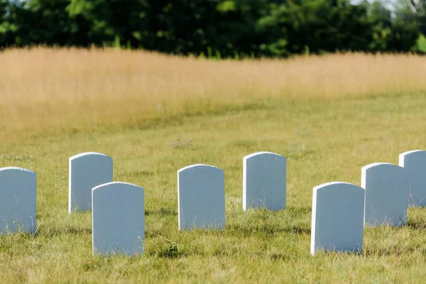 Lápides em branco na grama verde e céu azul no cemitério — Fotografia de Stock