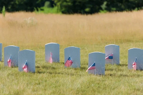 Pierres tombales sur herbe verte près des drapeaux américains dans le cimetière — Photo de stock