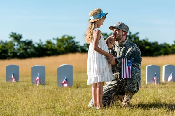 Military man in uniform looking at daughter near headstones in graveyard — Stock Photo