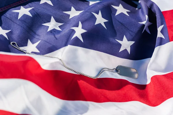 Silver badge on chain near american flag with stars and stripes — Stock Photo