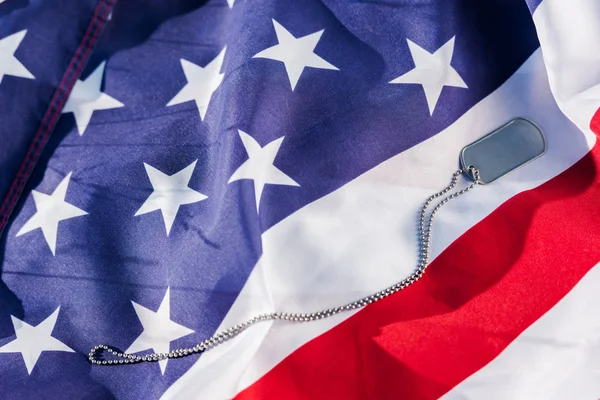 Metallabzeichen an Kette nahe der amerikanischen Flagge mit Sternen und Streifen — Stockfoto