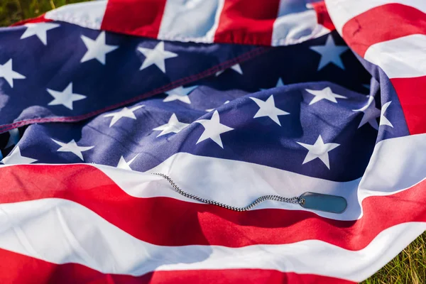 Placa militar en cadena cerca de bandera americana con estrellas y rayas - foto de stock