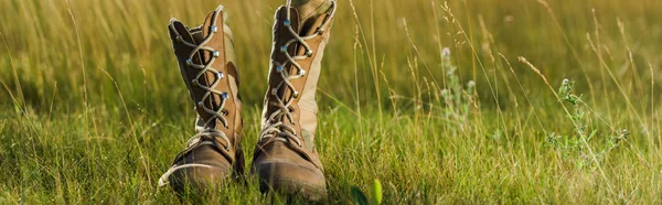 Панорамний знімок військових черевиків на зеленій траві — стокове фото