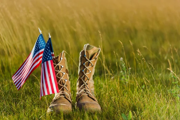 Botas militares perto da bandeira americana com estrelas e listras na grama — Fotografia de Stock