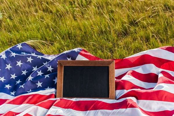 Kreidetafel auf amerikanischer Flagge mit Sternen und Streifen auf grünem Gras — Stockfoto