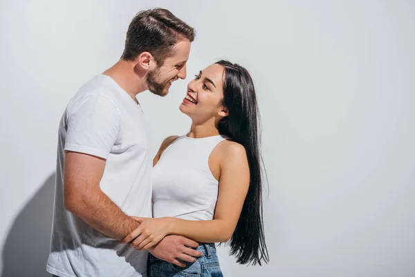 Jovem casal abraçando enquanto sorrindo e olhando um para o outro — Fotografia de Stock