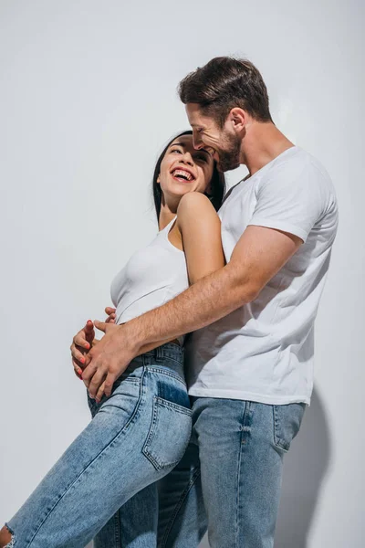 Jovem homem de pé atrás da namorada e abraçando-a enquanto olha um para o outro — Fotografia de Stock