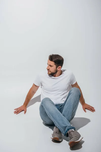 Красивый мужчина, сидящий на полу и отводящий взгляд — стоковое фото