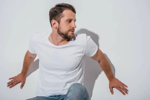 Handsome young man sitting on floor and looking away — Stock Photo