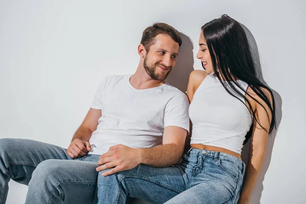 Dos jóvenes enamorados sentados en el suelo y mirándose - foto de stock