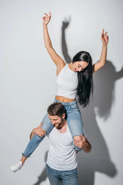 Schönes Mädchen sitzt auf den Schultern eines Jungen mit Händen in der Luft — Stockfoto