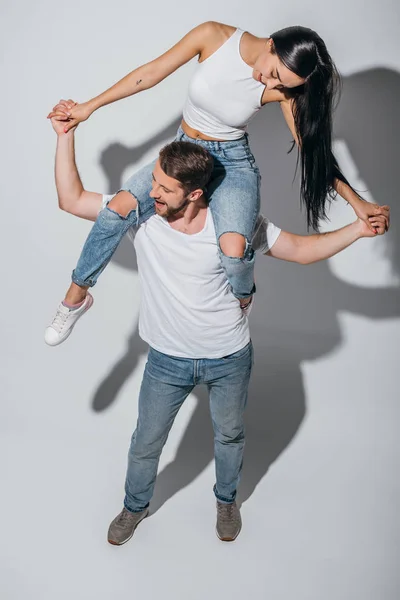 High angle view of young man holding girlfriend on shoulders while smiling and holding hands — Stock Photo