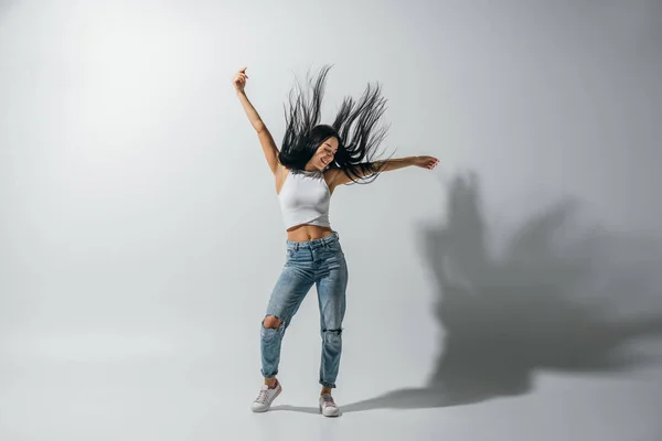 Vista completa de la chica bailando con las manos en el aire sobre fondo blanco - foto de stock