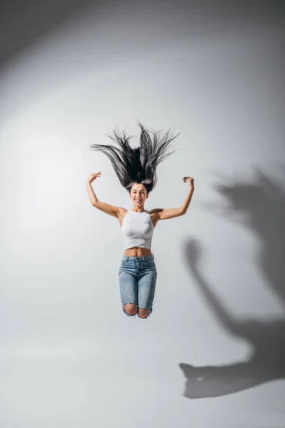 Visão comprimento total da menina feliz animado pulando com as mãos no ar — Fotografia de Stock