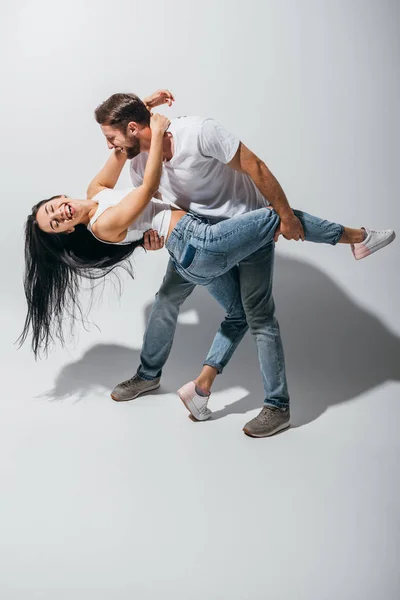 Visão de comprimento total do jovem casal rindo ao tentar dançar — Fotografia de Stock