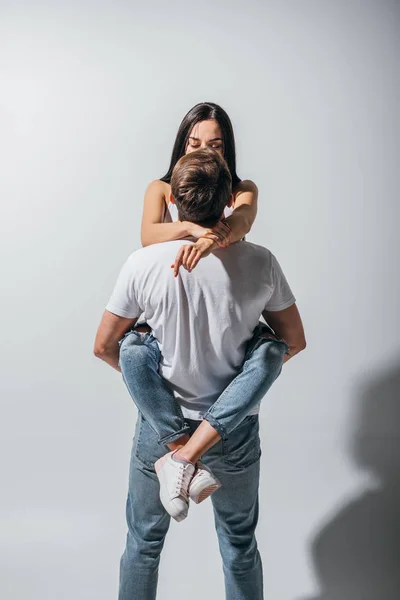 Молодой человек держит девушку на руках и целуется, стоя спиной к камере — стоковое фото