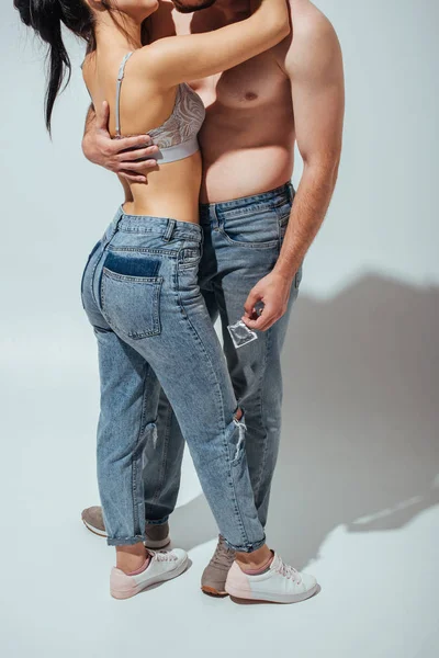 Cropped view of sexy couple kissing while naked man holding condom in hand — Stock Photo