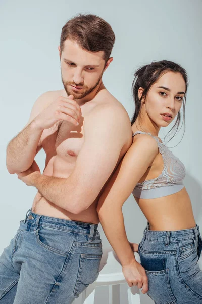 Handsome muscular guy looking away while girl standing near man and looking at camera — Stock Photo