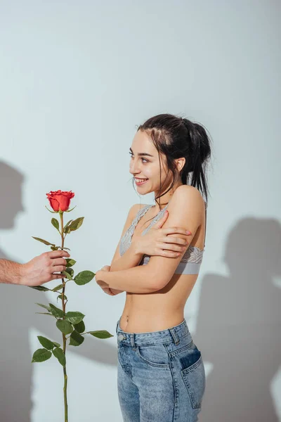 Обрізаний вид чоловіка, що дарує червону троянду сором'язливій дівчині — стокове фото
