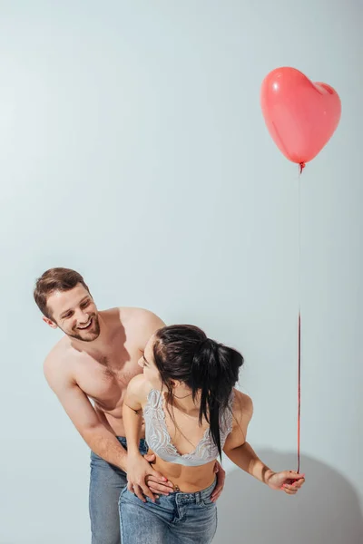 Sexy couple playing with each other and laughing while girl holding balloon in heart form — Stock Photo